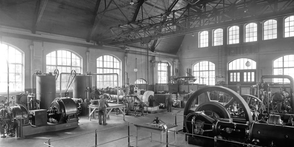 Interior of the old thermal power laboratory at the Norwegian Institute of Technology (NTH), showing machines and equipment and people at work. Photo: Unknown (original available in NTNU's special collections)