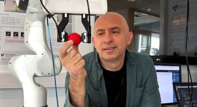Chief scientist Ekrem Misimi at SINTEF shows off the robot that can "feel" soft objects like a human hand does. Here the robot is holding a strawberry.